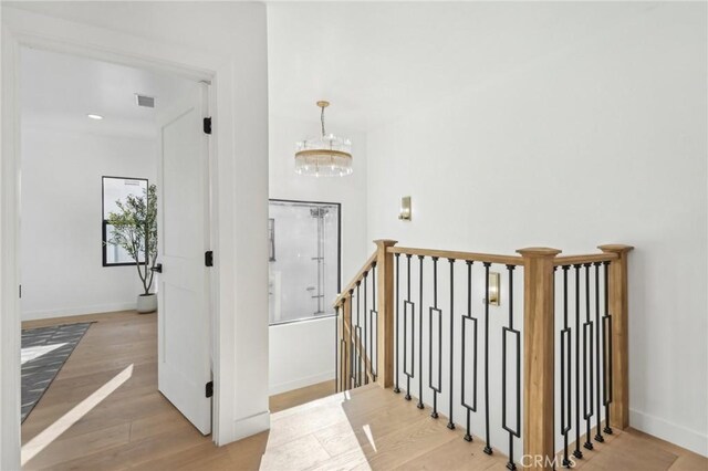 stairs featuring wood-type flooring and a chandelier