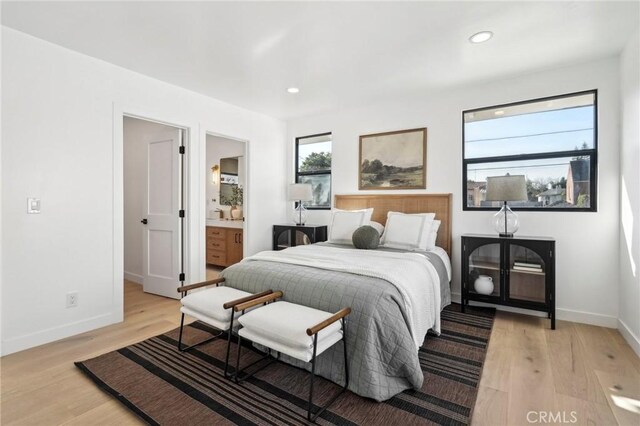 bedroom with multiple windows, ensuite bath, and light wood-type flooring