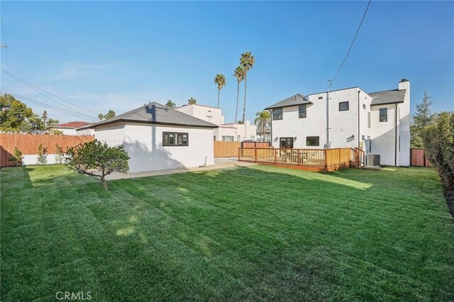 back of property featuring cooling unit, a wooden deck, and a lawn