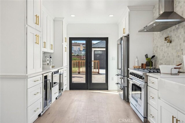 kitchen with white cabinets, appliances with stainless steel finishes, and wall chimney range hood