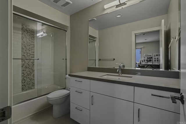 full bathroom with bath / shower combo with glass door, vanity, tile patterned floors, and toilet