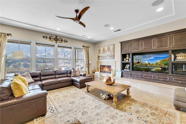 tiled living room with ceiling fan and a fireplace