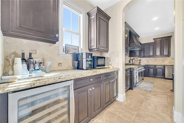 kitchen featuring wine cooler, light stone counters, dark brown cabinets, and stainless steel appliances