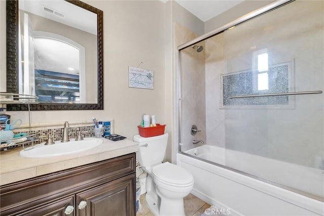 full bathroom with tile patterned flooring, vanity, combined bath / shower with glass door, and toilet