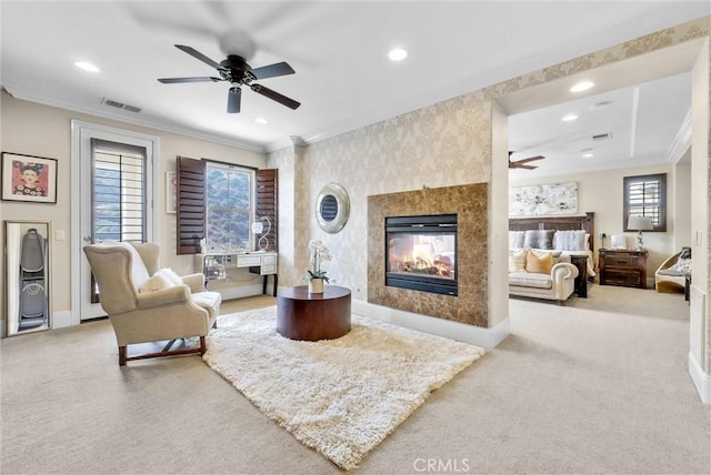 living room featuring ceiling fan, ornamental molding, a premium fireplace, and carpet