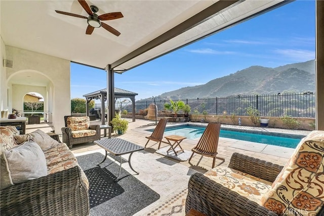 view of patio with a fenced in pool, ceiling fan, a gazebo, outdoor lounge area, and a mountain view