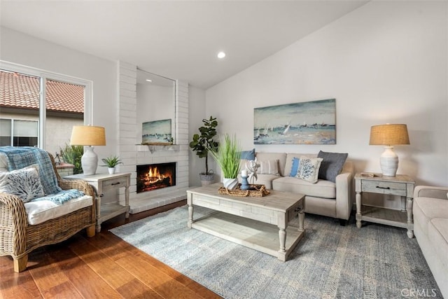 living room featuring vaulted ceiling, dark wood-type flooring, and a fireplace