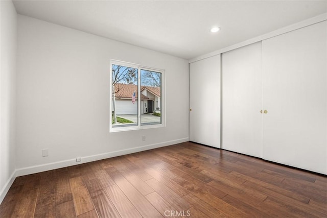 unfurnished bedroom with dark hardwood / wood-style flooring and a closet