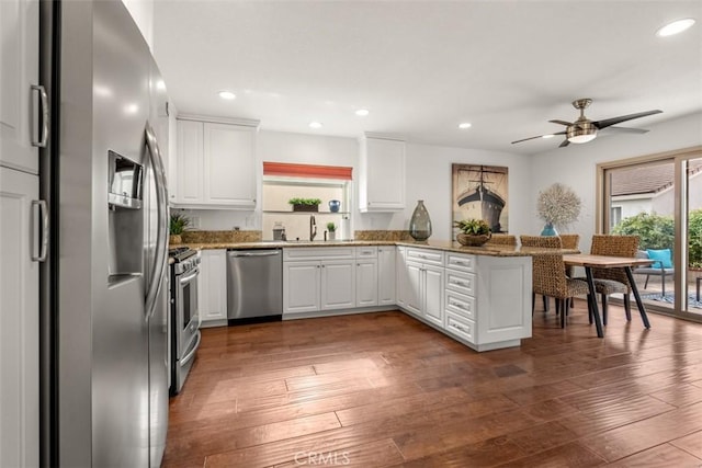 kitchen featuring dark hardwood / wood-style floors, sink, white cabinets, kitchen peninsula, and stainless steel appliances