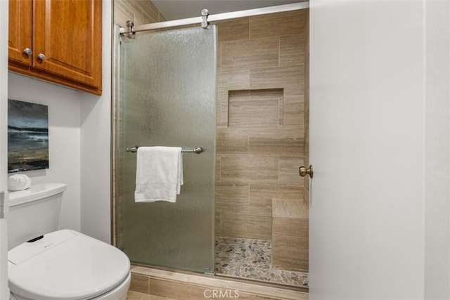 bathroom featuring toilet and a shower with shower door