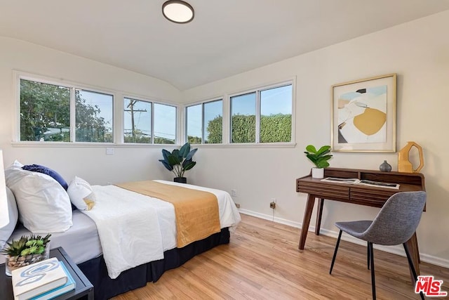 bedroom with vaulted ceiling, light hardwood / wood-style floors, and multiple windows