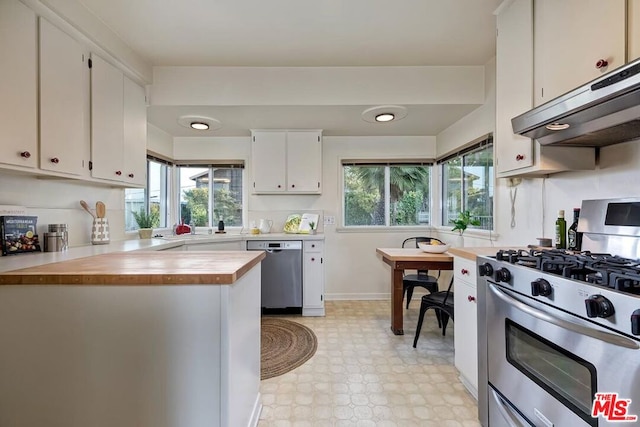 kitchen with white cabinetry, butcher block countertops, and appliances with stainless steel finishes