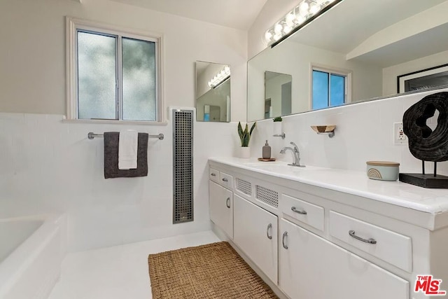 bathroom featuring a tub to relax in, vanity, and tile walls