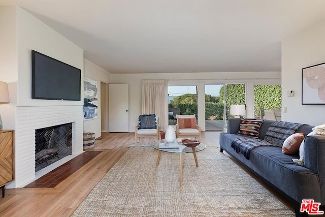 living room featuring a brick fireplace and light hardwood / wood-style floors