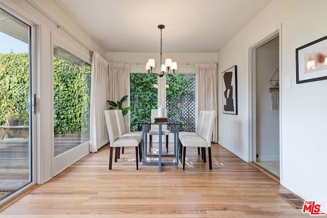 dining area featuring a notable chandelier, plenty of natural light, and light wood-type flooring