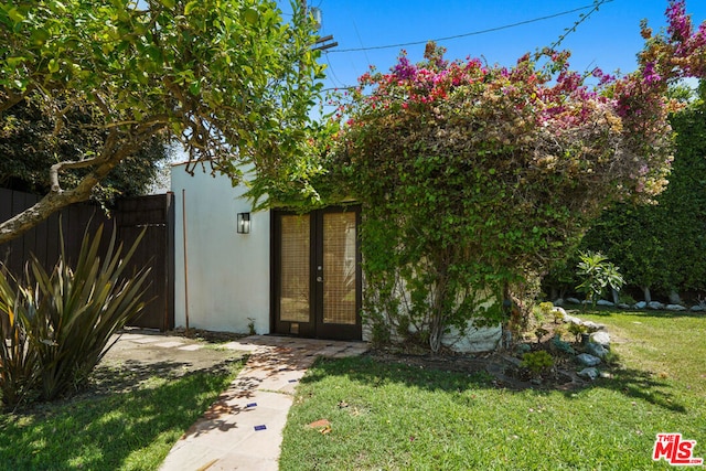 view of exterior entry with a yard and french doors