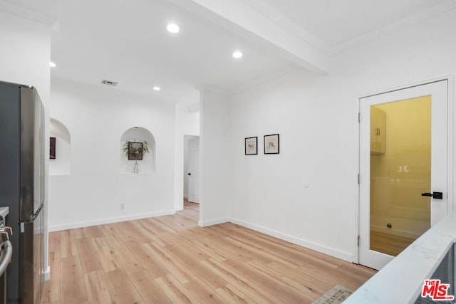 spare room with beam ceiling, ornamental molding, and light hardwood / wood-style floors