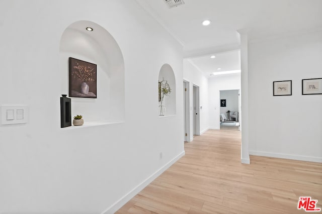 hall featuring crown molding and light hardwood / wood-style flooring