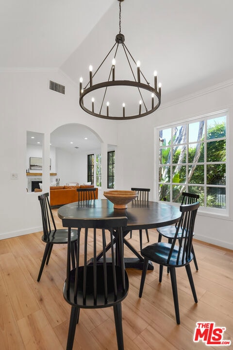 dining room featuring ornamental molding, vaulted ceiling, and light hardwood / wood-style flooring