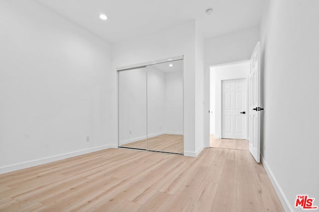 unfurnished bedroom with a closet and light hardwood / wood-style flooring