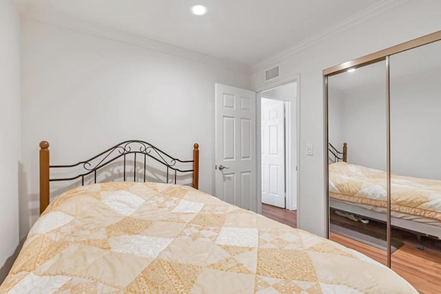 bedroom featuring crown molding, a closet, and hardwood / wood-style flooring