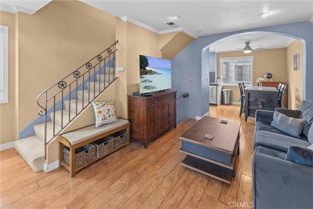 living room featuring ceiling fan, ornamental molding, and light wood-type flooring