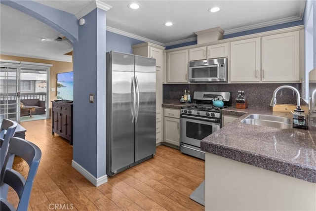 kitchen featuring sink, crown molding, appliances with stainless steel finishes, light hardwood / wood-style floors, and decorative backsplash