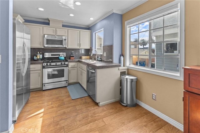 kitchen with sink, backsplash, stainless steel appliances, light hardwood / wood-style floors, and ornamental molding