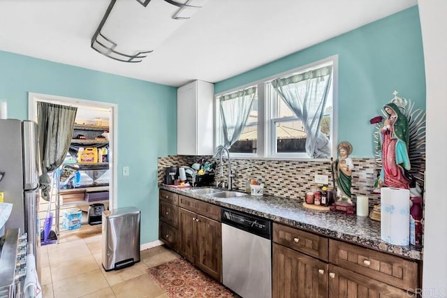 kitchen with sink, dark brown cabinets, light tile patterned floors, dishwasher, and backsplash