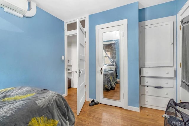 bedroom featuring a wall mounted air conditioner and light wood-type flooring