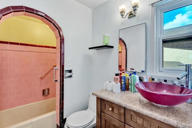 full bathroom featuring vanity, tiled shower / bath, a wealth of natural light, and toilet