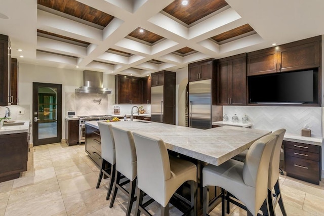 kitchen featuring sink, decorative backsplash, a kitchen breakfast bar, and wall chimney exhaust hood