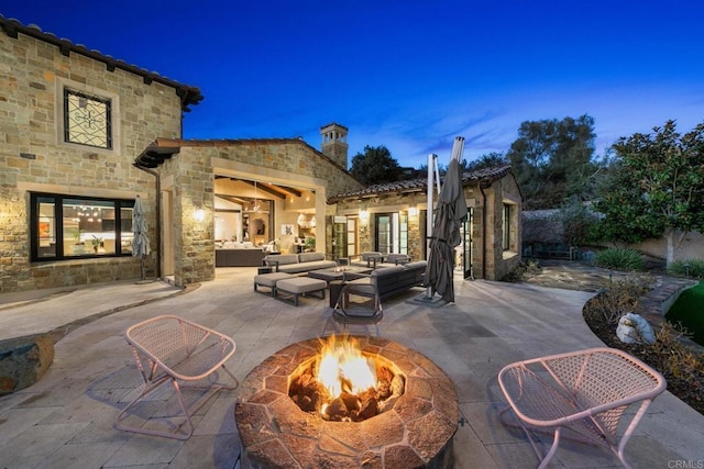 patio terrace at dusk featuring an outdoor living space with a fire pit