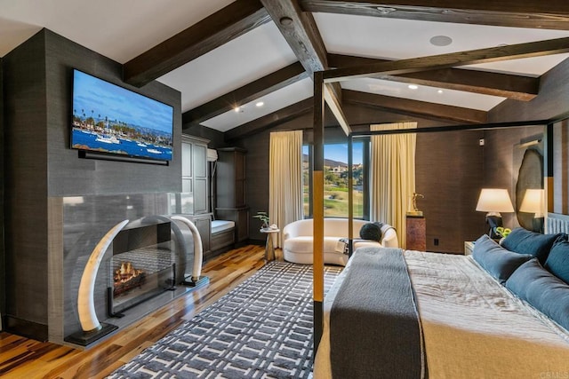 bedroom with a fireplace, hardwood / wood-style floors, and vaulted ceiling with beams