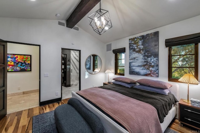 bedroom with an inviting chandelier, connected bathroom, light hardwood / wood-style floors, and vaulted ceiling with beams