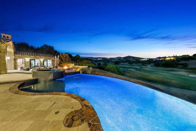 pool at dusk with a patio area