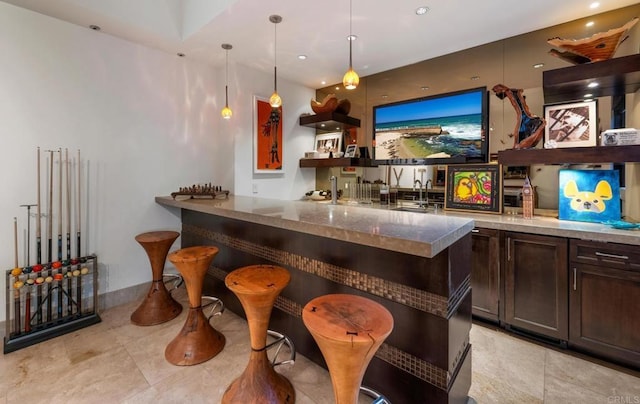 bar featuring decorative light fixtures, sink, and dark brown cabinets