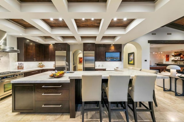 kitchen with light stone counters, stainless steel appliances, a kitchen bar, and a large island with sink