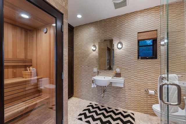 interior space featuring sink, tile walls, tile patterned flooring, walk in shower, and toilet