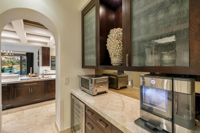 interior space featuring wine cooler, dark brown cabinetry, coffered ceiling, and beam ceiling