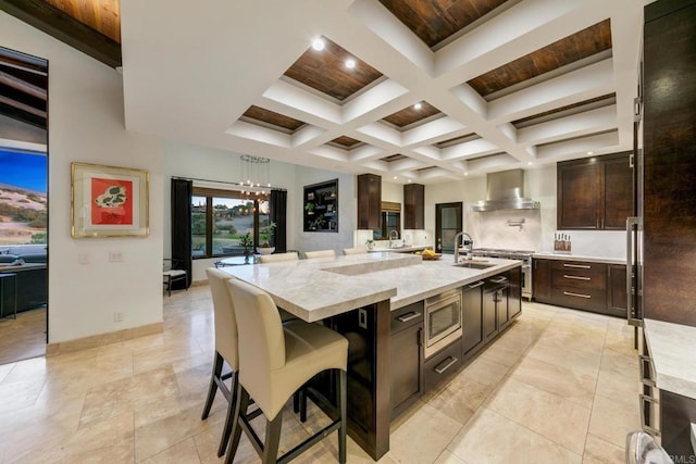 kitchen with sink, a breakfast bar area, stainless steel appliances, a large island, and wall chimney range hood