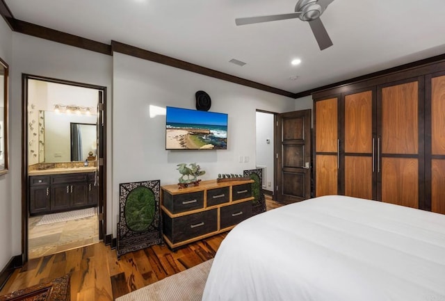 bedroom with ensuite bath, dark wood-type flooring, ornamental molding, and ceiling fan