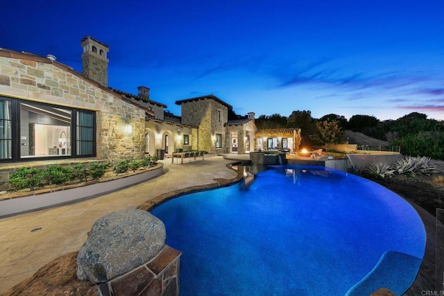 pool at dusk with a patio area