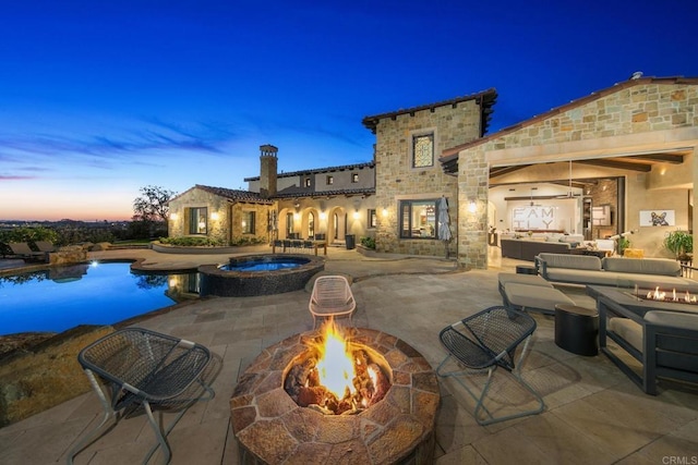 pool at dusk with an in ground hot tub, an outdoor fire pit, and a patio area