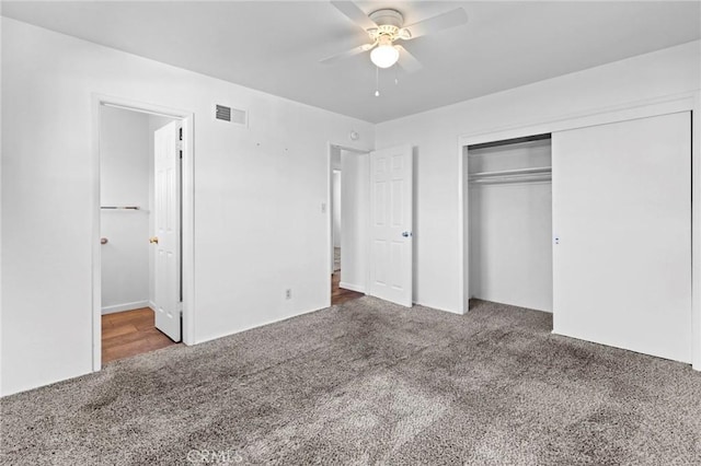 unfurnished bedroom with ceiling fan, ensuite bath, a closet, and dark colored carpet