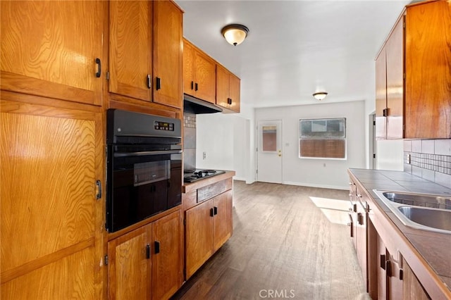 kitchen featuring sink, backsplash, dark hardwood / wood-style flooring, tile countertops, and oven