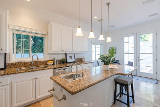 kitchen with dark stone counters, sink, an island with sink, and white cabinets