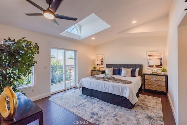 bedroom featuring dark wood-type flooring, vaulted ceiling with skylight, access to exterior, and ceiling fan