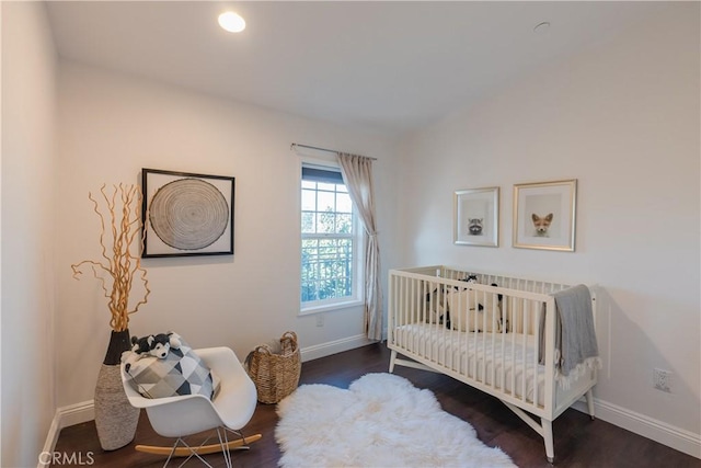 bedroom featuring a crib and dark wood-type flooring