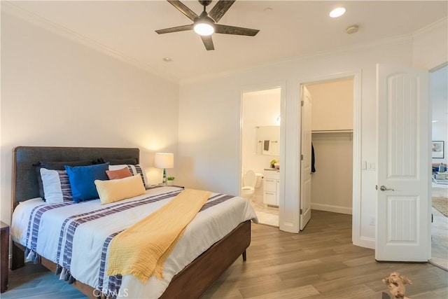 bedroom featuring hardwood / wood-style floors, ornamental molding, a spacious closet, ceiling fan, and ensuite bath